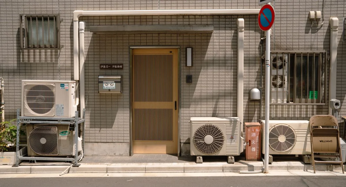 A minimalist facade with air conditioners and a no parking sign in Tokyo, Japan.